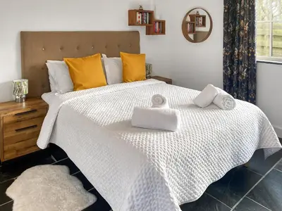 a bedroom with a large white bed with towels on it at The Milking Parlour in St Ives
