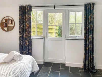 a bedroom with sliding doors and a window at The Milking Parlour in St Ives