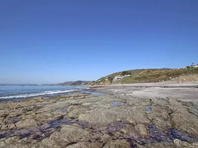 a beach with rocks and the ocean on a clear day at Watchtower in Torpoint