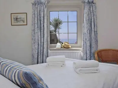 a bedroom with a bed with a window and towels at Watchtower in Torpoint