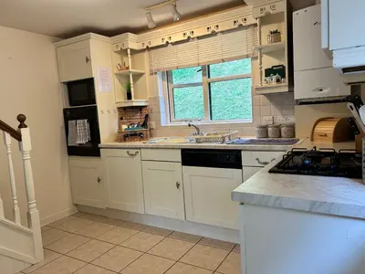 a kitchen with white cabinets and a sink and a window at Looe, Cornwall, Cottage, couples, romantic, quiet location, views, reliable Wi-Fi in Looe