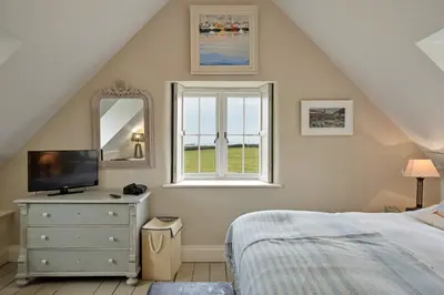 a bedroom with a bed and a dresser and a window at Finest Retreats - St Eval School House in Saint Ervan