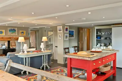 a kitchen and living room with a red table at Finest Retreats - St Eval School House in Saint Ervan