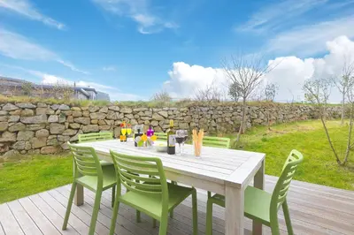 a wooden table with green chairs on a wooden deck at 64 Una in Carbis Bay
