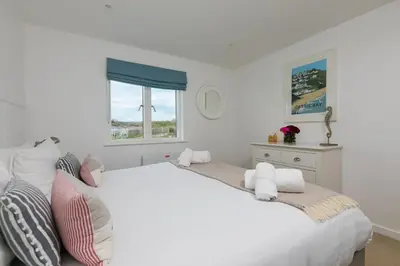 a white bedroom with a large white bed and a window at 64 Una in Carbis Bay