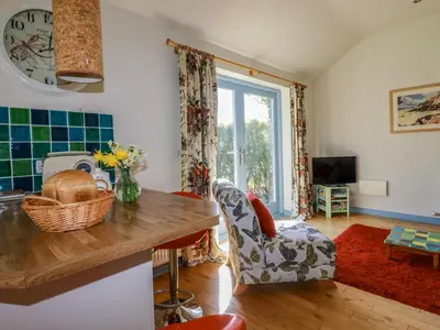 a kitchen with a table and a chair and a window at Stargazy Skies in St. Agnes