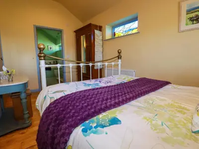 a bedroom with a bed with a purple blanket on it at Stargazy Skies in St. Agnes