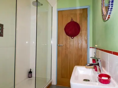 a bathroom with a sink and a shower with a wooden door at Stargazy Skies in St. Agnes
