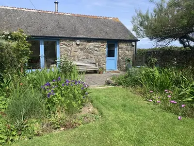 a stone cottage with a blue door and a bench at Stargazy Skies in St. Agnes