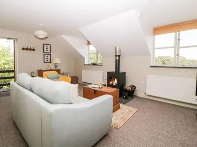 a living room with a white couch and a fireplace at The Hayloft in Lostwithiel