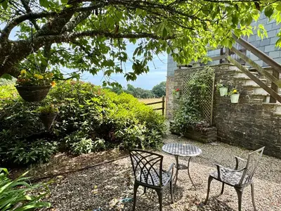 two chairs and a table in a garden at The Hayloft in Lostwithiel