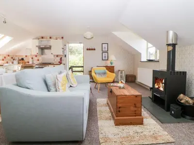 a living room with a couch and a fireplace at The Hayloft in Lostwithiel