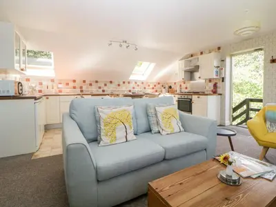 a living room with a blue couch and a kitchen at The Hayloft in Lostwithiel