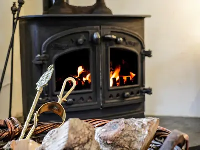 a fireplace with a fire in it with some rocks at The Mill in Lostwithiel