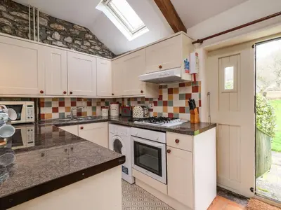 a kitchen with white cabinets and a stove top oven at The Mill in Lostwithiel