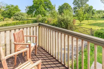 a deck with two chairs and a view of a field at 2 Bed in Launceston oc-t31002 in Lewannick