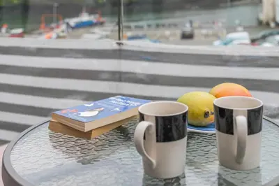 two coffee cups on a table with books and fruit at 2 Bed in Fowey oc-o31260 in Fowey