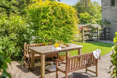 a wooden table and two benches in a garden at 2 Bed in Launceston oc-d31000 in Lewannick