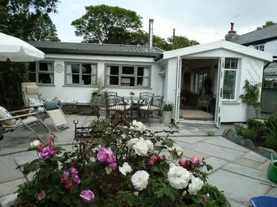 a white house with a patio with flowers at Birdsong in St. Issey