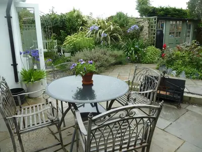 a table and chairs with a vase of flowers on it at Birdsong in St. Issey