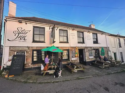 a building with two people and a dog in front of it at The Star Inn in Saint Erth