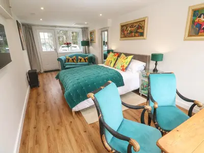 a bedroom with a bed and two chairs at Elder Cottage Studio in Truro