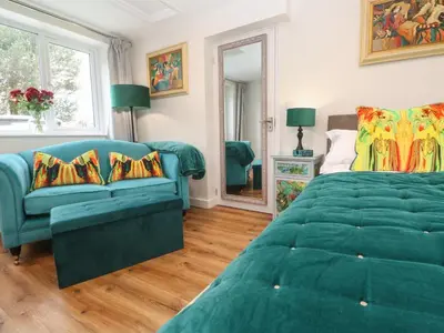 a bedroom with a green bed and a couch at Elder Cottage Studio in Truro