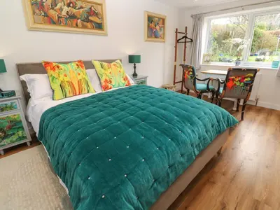 a bedroom with a large green blanket on a bed at Elder Cottage Studio in Truro