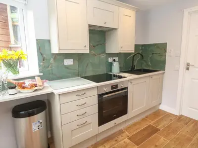 a kitchen with white cabinets and a sink at Elder Cottage Studio in Truro