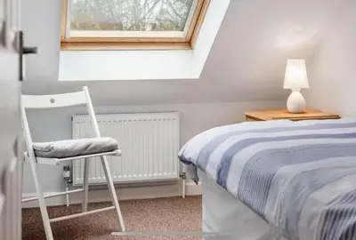 a bedroom with a bed and a chair and a window at Family Home in Hayle close to Gwithian Beach in Phillack