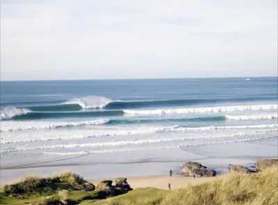 a beach with people walking on the sand and waves at Family Home in Hayle close to Gwithian Beach in Phillack