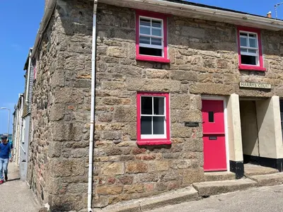 a stone building with red doors and windows at Penty Men Growyn in St Ives
