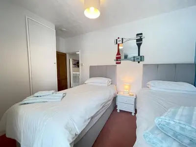 a bedroom with two beds and a cross on the wall at Penty Men Growyn in St Ives