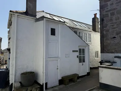 a small white building with a door next to a building at Norway House Studio in St Ives