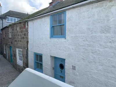 a white building with blue windows and a blue door at Windjammer in St Ives