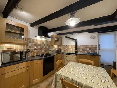 a kitchen with wooden cabinets and a table and a dining room at Windjammer in St Ives