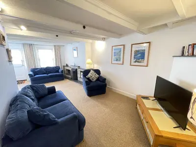 a living room with blue couches and a tv at Windjammer in St Ives