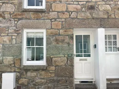 a stone building with a white door and windows at Howards Way in St Ives