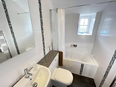a white bathroom with a toilet and a sink at Howards Way in St Ives