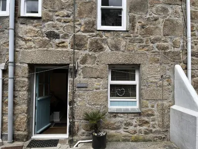 a stone building with two windows and a plant in the doorway at Howards Way in St Ives