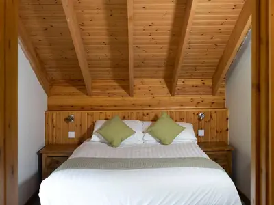 a bed in a room with a wooden ceiling at Deerpark Cabins, Cornwall - Forest Holidays in Liskeard