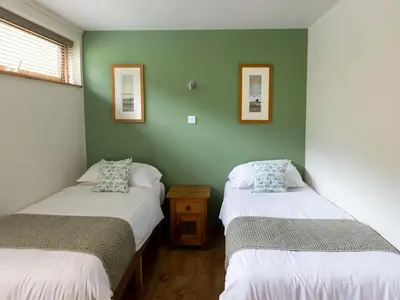two twin beds in a room with green walls at Deerpark Cabins, Cornwall - Forest Holidays in Liskeard