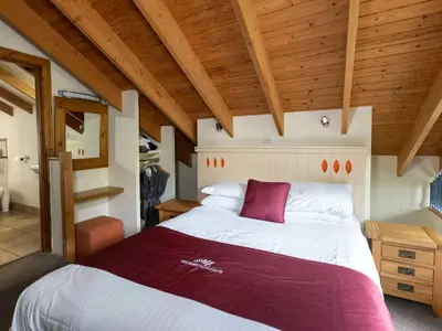 a bedroom with a large bed in a room with wooden ceilings at Deerpark Cabins, Cornwall - Forest Holidays in Liskeard