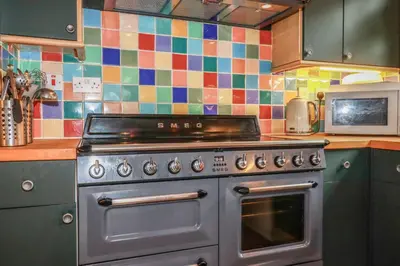 a kitchen with a stainless steel stove and colorful tiles at 6 The Links in Penzance