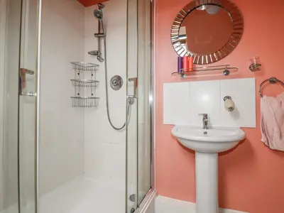 a bathroom with a sink and a shower with a mirror at 6 The Links in Penzance