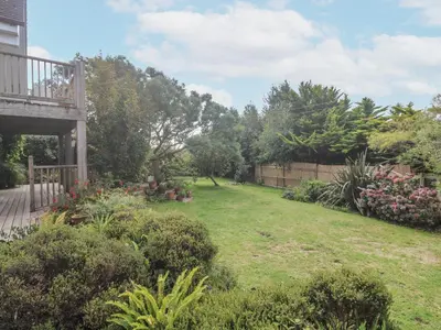 a backyard with a yard with flowers and a fence at 6 The Links in Penzance