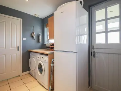 a kitchen with a refrigerator and a washing machine at Coastman's Nest in Newquay