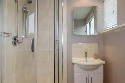 a bathroom with a shower and a sink and a mirror at Coastman's Nest in Newquay