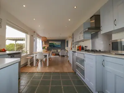 a kitchen with white cabinets and a dining room at Coastman's Nest in Newquay