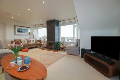 a living room with a television and a table at Coastman's Nest in Newquay